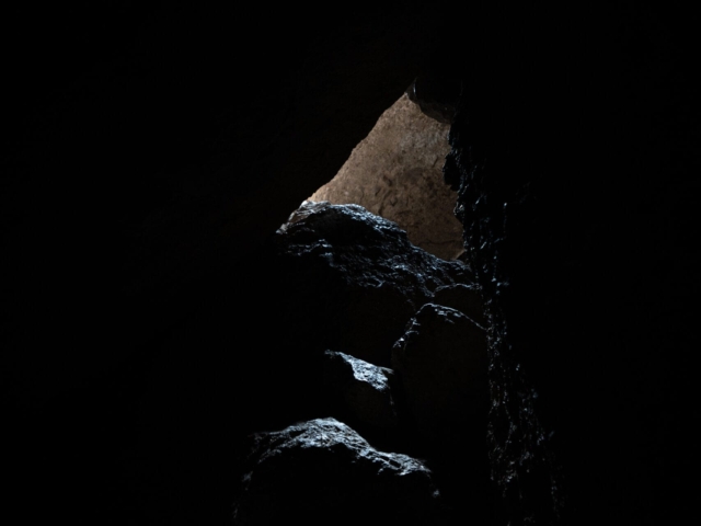 A small column of light shines down on some rocks in a cave