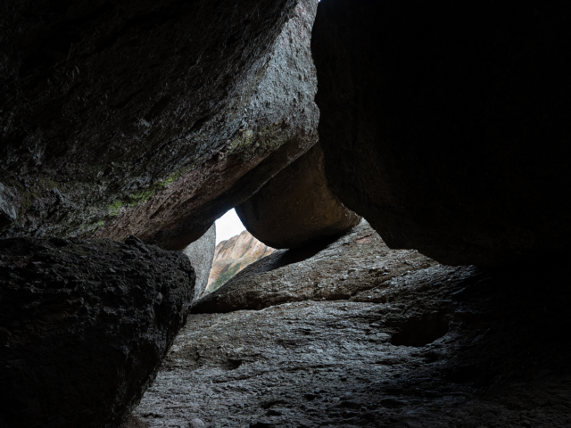 Light shines through the shadow of boulders revealing a mountain